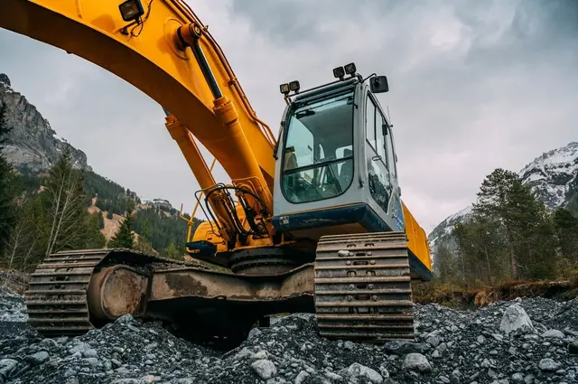 Excavator working on rocky ground with mountains behind