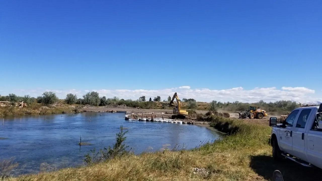 Excavator restoring a river bank beside calm water